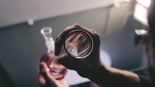 How to Use a Bong: A Step-by-Step Guide for Smoking Weed' by The DART Company, demonstrating the process of grinding cannabis with a grinder.